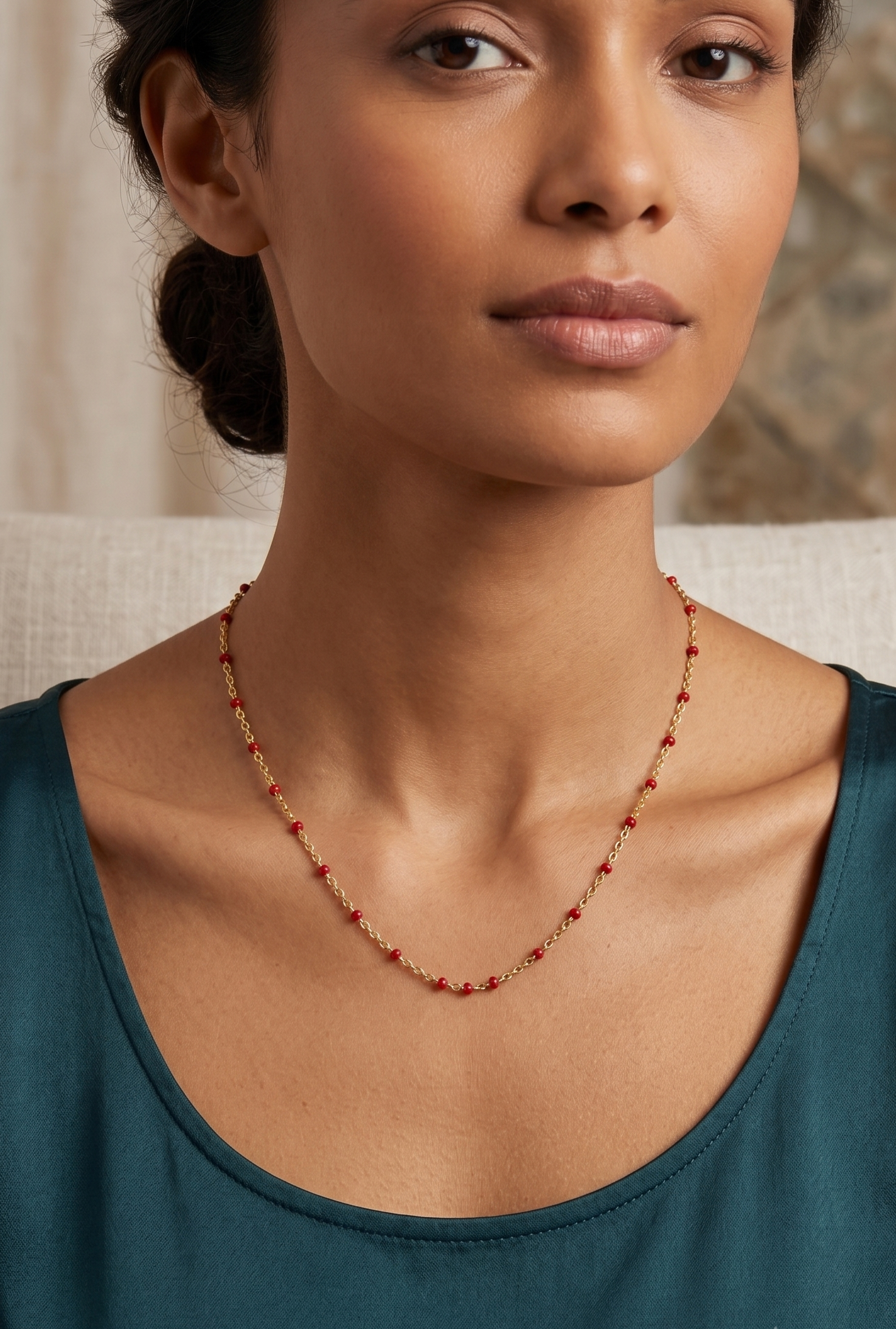 Model wearing gold red enamel bead station necklace with teal top