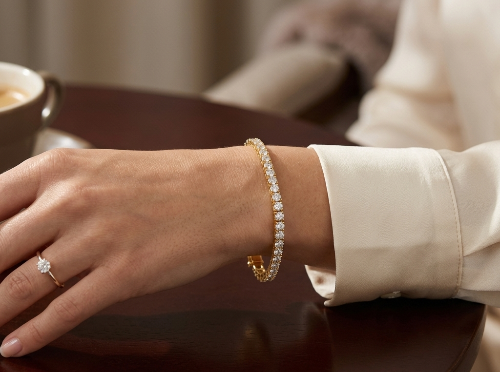 Gold classic tennis bracelet worn on wrist with white blouse