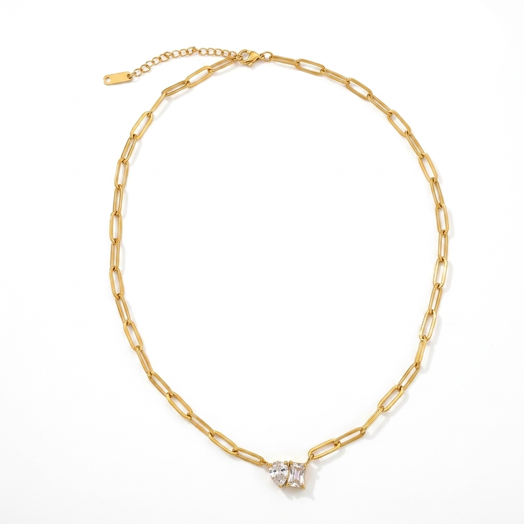 Gold paperclip chain crystal pendant necklace flat lay on white background