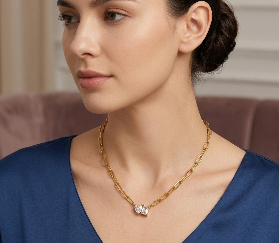Model wearing gold paperclip chain crystal pendant necklace with blue top