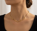 Model wearing gold leaf charm necklace with black top