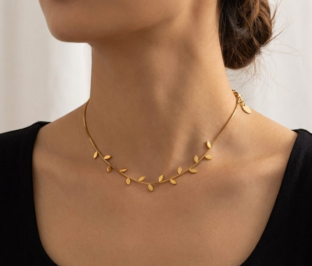 Model wearing gold leaf charm necklace with black top