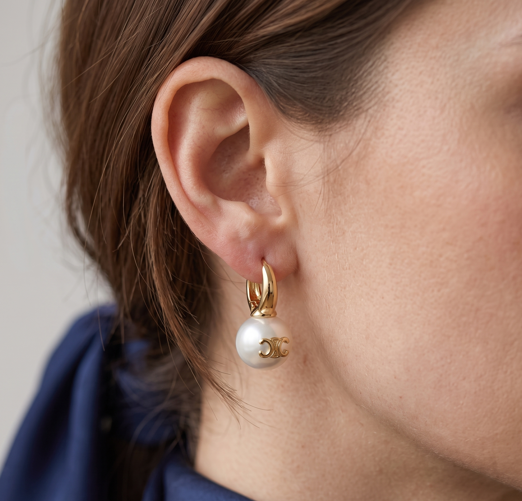Gold huggie pearl charm earrings worn on model
